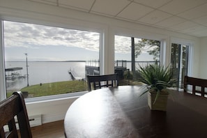 A dining area with a view of a lake, a potted plant, and a wooden table. - North Shore Haven - Stunning 3 Bdrm Waterfront Home! (Midland)