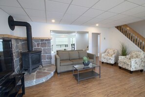 A living room with a stone fireplace, a sofa, two armchairs, and a coffee table. - North Shore Haven - Stunning 3 Bdrm Waterfront Home! (Midland)
