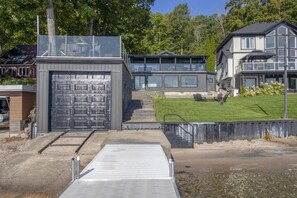 A modern building with a garage, a covered outdoor area, and a grassy lawn. - North Shore Haven - Stunning 3 Bdrm Waterfront Home! (Midland)