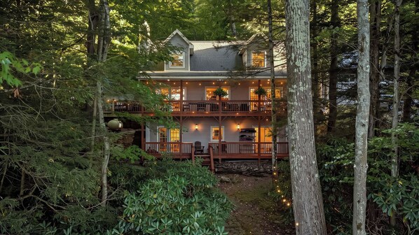 A two-story wooden house surrounded by dense forest, with a balcony on the upper floor. - Covewood by Avantstay Lakefront w/ Private Shoreline Kayaks + Paddle Boards + Firepit (Lakeville)