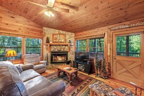 A cozy cabin interior with a fireplace, leather furniture, and a stone wall. - Disconnect at Bearly Connected (Ellijay)