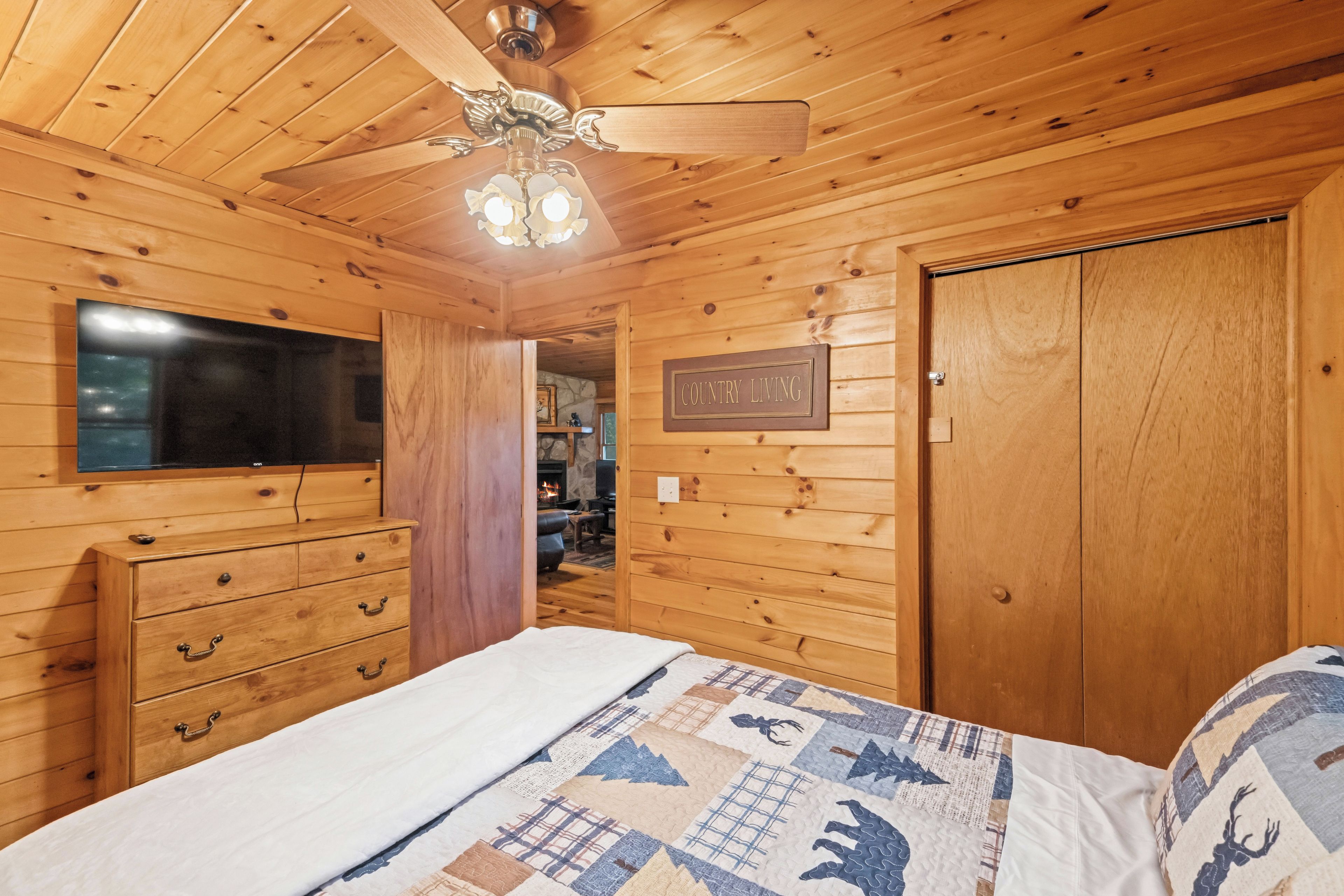 A wooden interior with a bed, dresser, and a sign reading 'COUNTRY LIVING'.