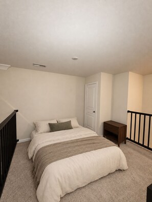 Une chambre à coucher avec un lit, une table de chevet, une porte et un escalier.