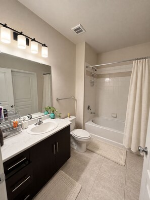 Une salle de bain moderne équipée d’un meuble-lavabo à deux vasques, de toilettes, d’une baignoire et d’une douche.