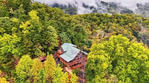 A wooden cabin with a green roof surrounded by dense forest. - Eagles View by Avantstay 5-acre Smoky Cabin Hot Tub + Mountain Views Near Pigeon Forge (Sevierville)