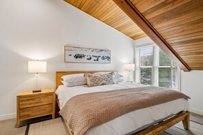 A bedroom with a wooden ceiling, a bed with white bedding and a patterned throw, two bedside lamps, and a wall-mounted picture of wildlife. - Empire House 2BR | Sleeps 6 | Walk to Park City Mountain | Free Bus (Park City)