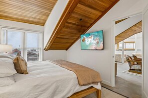 Un dormitorio con cama, un cuadro y vista al exterior.