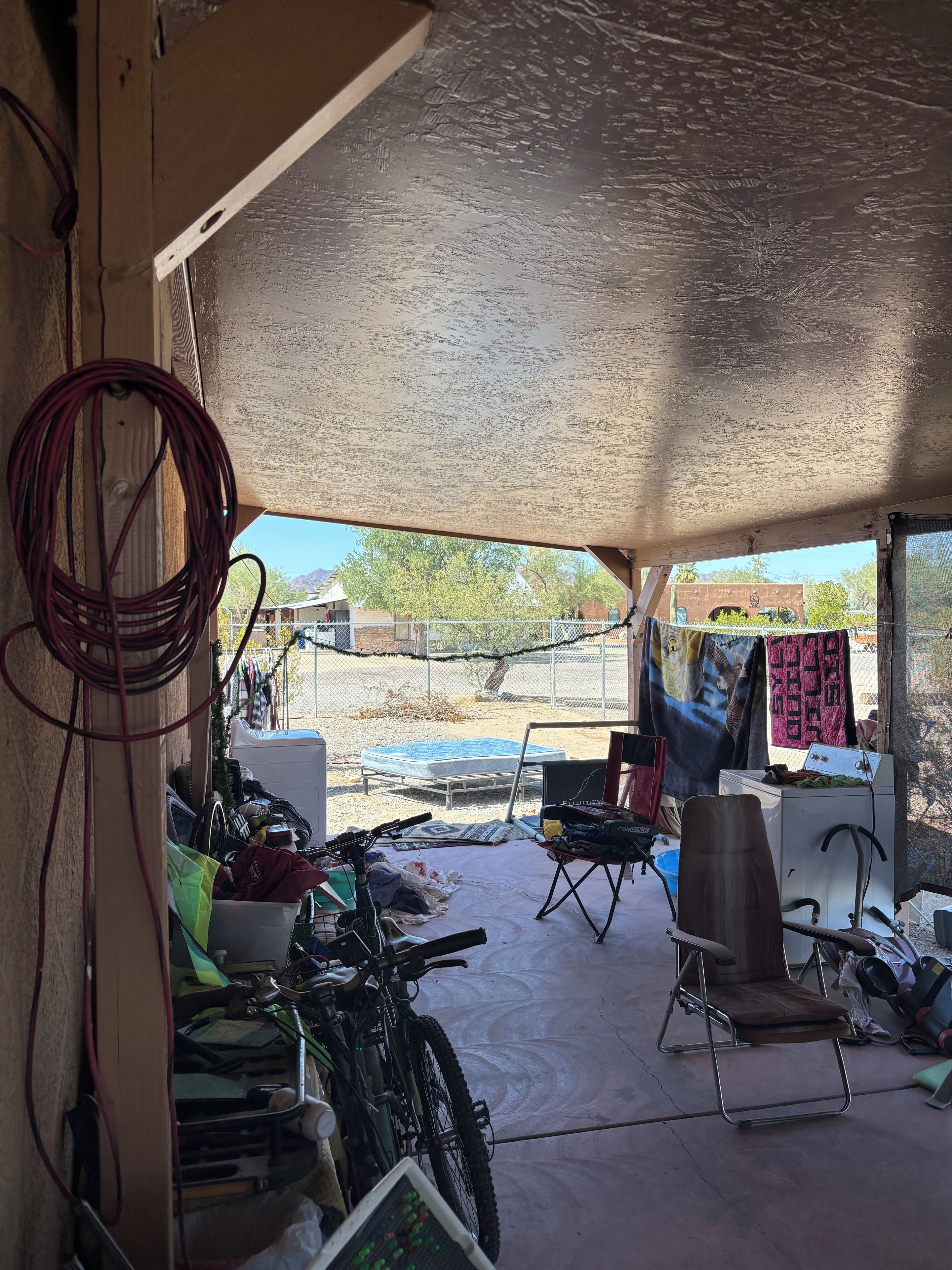 Un garaje desordenado con una motocicleta, una silla plegable y diversos objetos esparcidos.