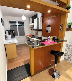 A compact kitchen with a central island, wooden cabinetry, and a black countertop.