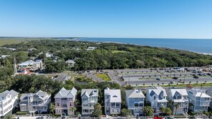 A coastal residential area with houses, a parking lot, and a view of the ocean. - Merri Mac Cottage | Coast Cottages Beach Access, Pool & Pavilion (Saint Simons Island)