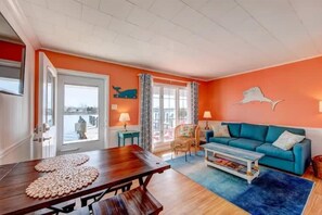 Ein Zimmer mit einem Holzesstisch, einem blauen Sofa und Blick durch eine Tür.