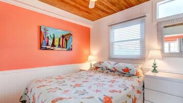 Ein Schlafzimmer mit einem Bett, einem Bild an der Wand, einem Fenster mit Jalousien und einem Deckenventilator.