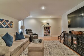 A living room with a sofa, ottoman, and a flat-screen TV. - Glorious Views 5-bedroom house in perfect Black Mountain (Black Mountain)