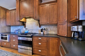 A kitchen with wooden cabinets, a gas stove, stainless steel appliances, and a coffee maker. - Glorious Views 5-bedroom house in perfect Black Mountain (Black Mountain)