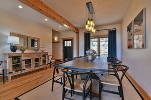 A dining room with a long wooden table, black chairs, and a chandelier. - Glorious Views 5-bedroom house in perfect Black Mountain (Black Mountain)