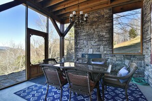 A dining area with a stone wall, wicker chairs, and a glass table. - Glorious Views 5-bedroom house in perfect Black Mountain (Black Mountain)