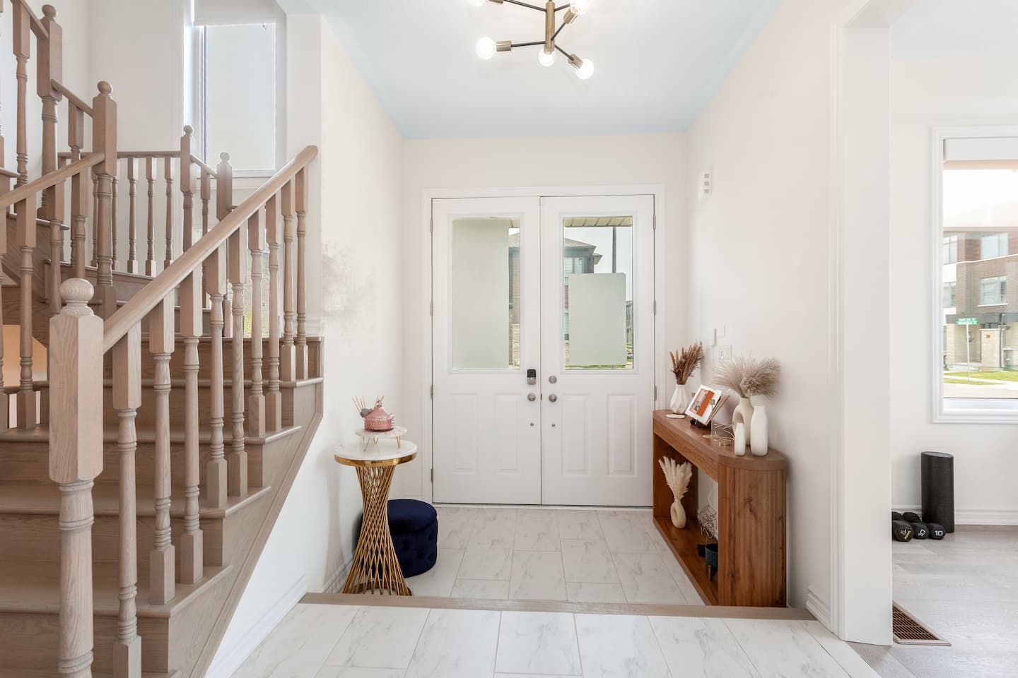 A staircase leading to a second floor, a white door with frosted glass panels, and a small round table with a decorative item.