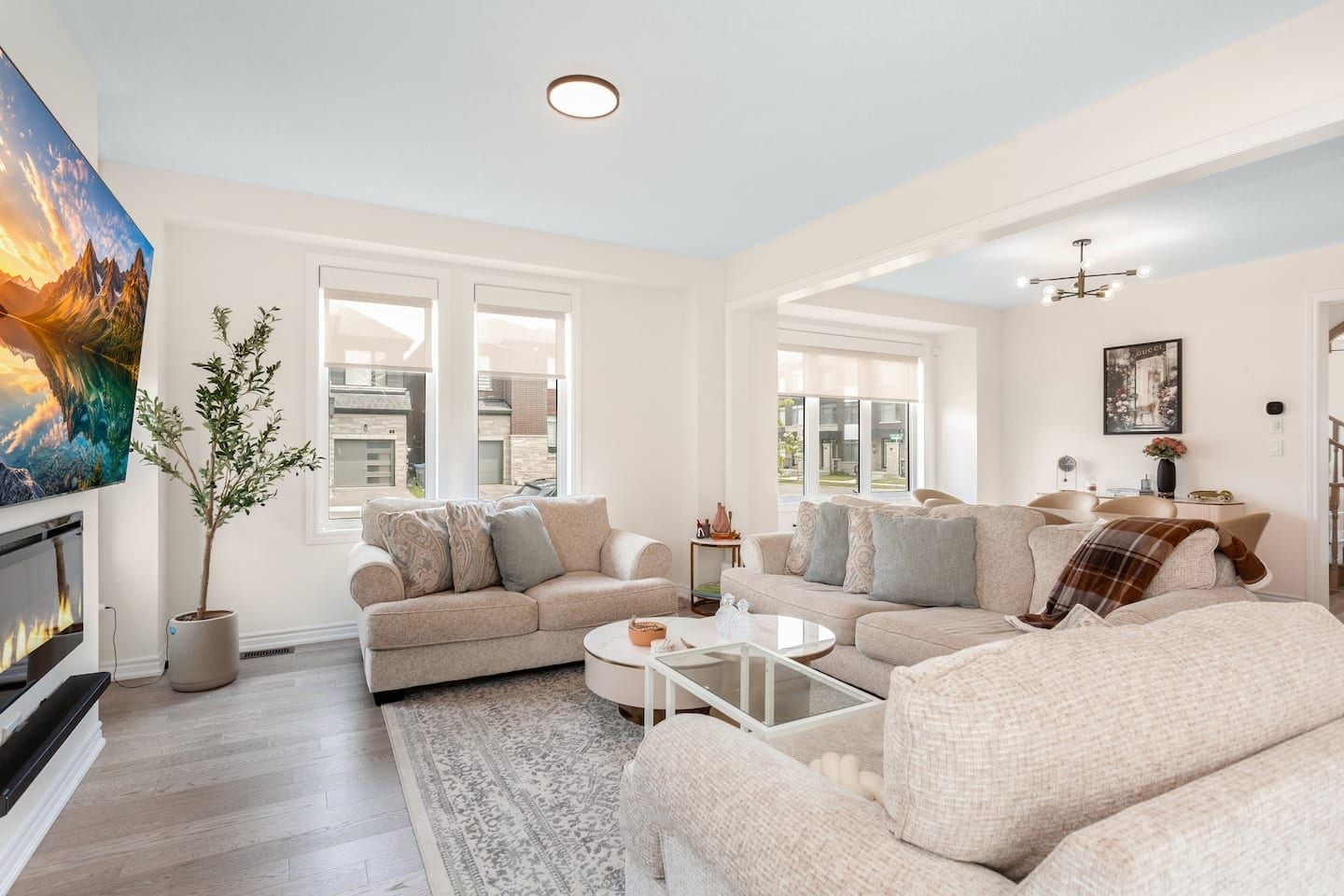 A living room with a fireplace, large windows, and a modern chandelier.