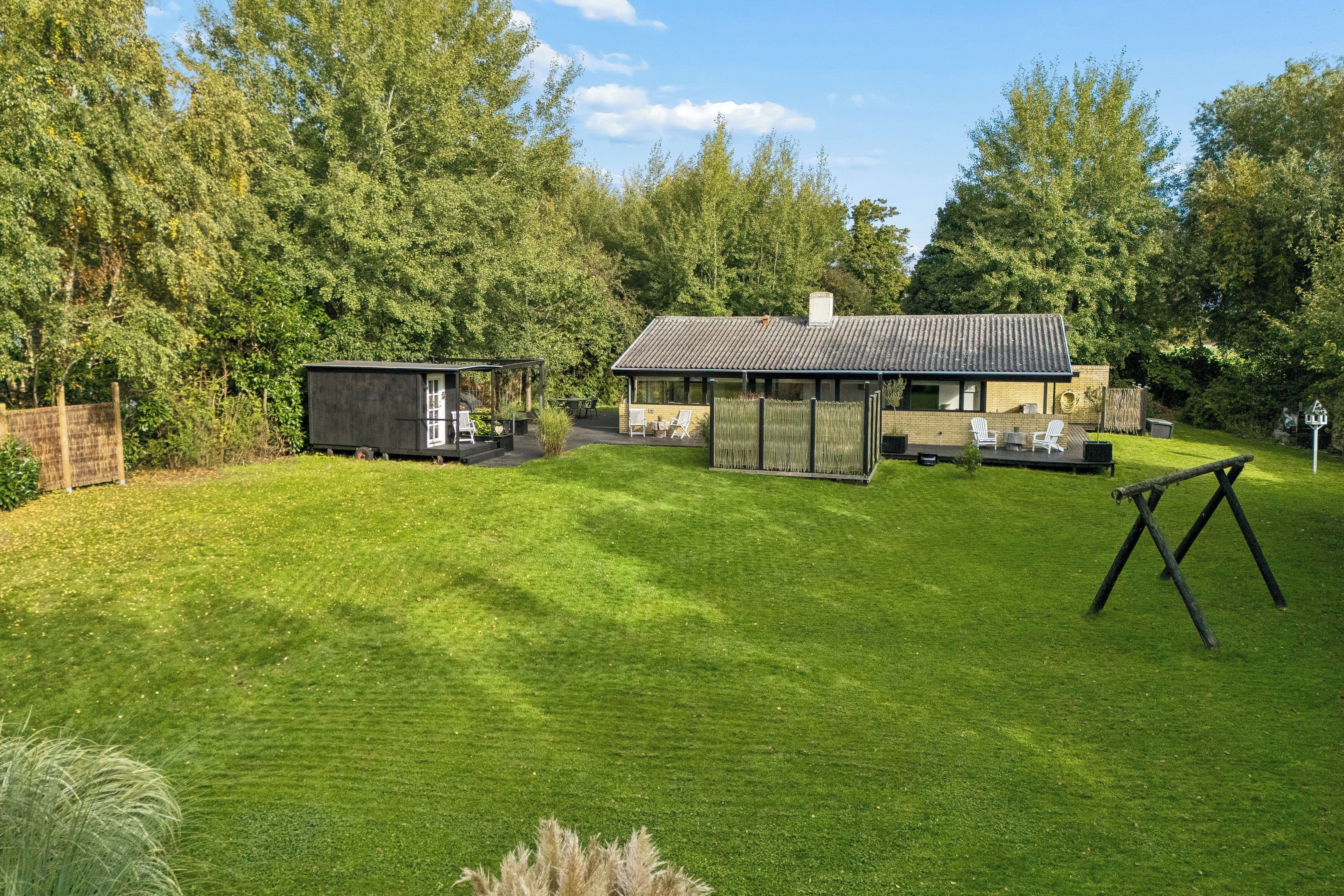 A modern house with a well-maintained lawn, outdoor seating area, and a swing set.