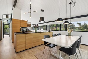 A modern kitchen with wooden cabinets, a central island, and pendant lighting. - Lovely Holiday Home with Hot Tub – 200m from Sea (Tranekær)