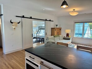 A modern kitchen with a black countertop, wooden cabinets, and a bull skull decoration. - The Choo Choo House- Luxe renovated home w/ ADU, Sleeps 10, AC, Wrap-around Deck (Livingston)