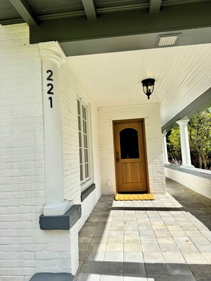Un edificio blanco con el número 221, una puerta de madera y un accesorio de iluminación encima.