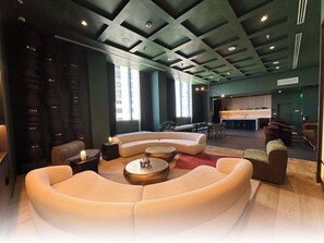 Un espace de détente moderne avec un ensemble de canapés aux lignes courbes, des tables basses rondes et un bar en arrière-plan.