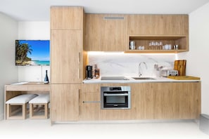 Une cuisine moderne avec des meubles de rangement en bois, un four Bosch, un évier et un plan de travail sur lequel se trouve un grille-pain.