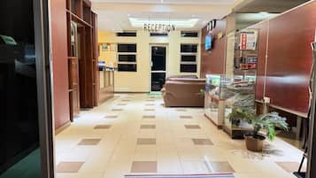 Zona de recepción de hotel con mostrador, área de asientos y exhibición de productos.
