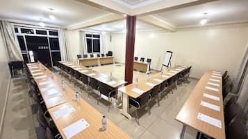 Une salle de conférence équipée de plusieurs tables, de chaises et d’un tableau blanc.