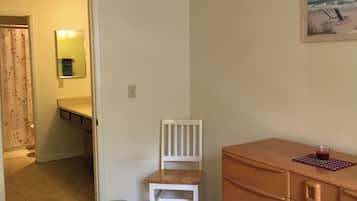 A bedroom with a bed, a wooden dresser, a chair, and a painting on the wall.