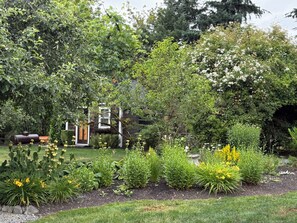 A garden with a variety of plants, a wooden structure, and a metal sculpture.