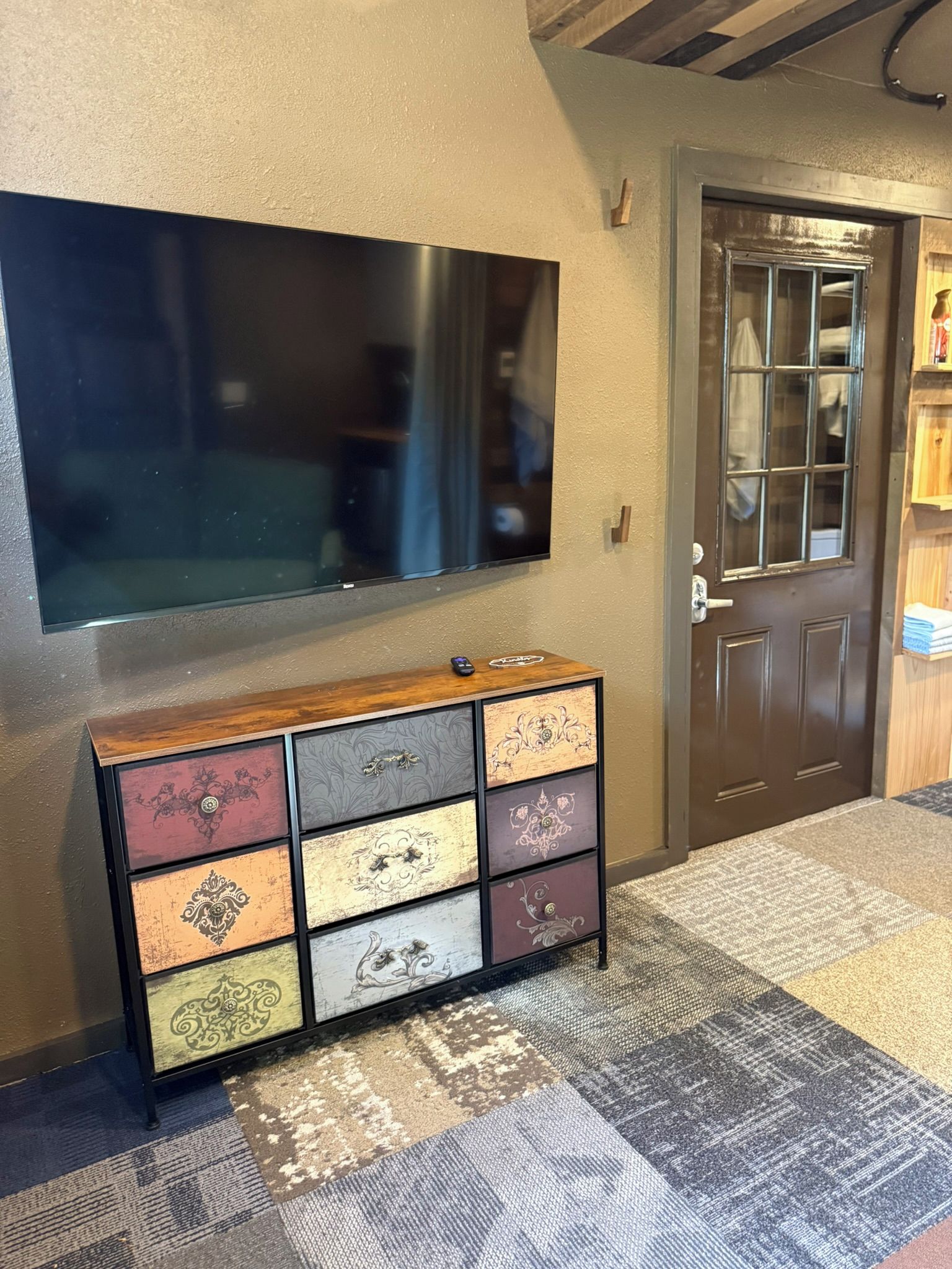 Un televisor de pantalla plana montado en la pared sobre un aparador de madera con detalles decorativos.
