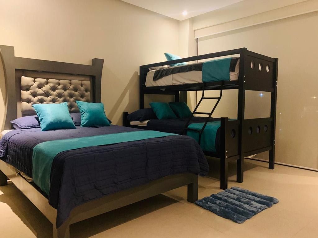 Une chambre avec un lit superposé, un lit simple et une tête de lit.