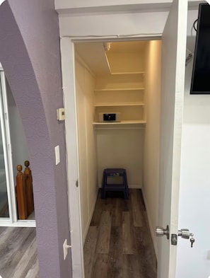 A narrow hallway with a wooden floor, a small step stool, and a shelf unit with a power strip. - Soothing 1-bedroom studio with AC in charming Guttenberg (Guttenberg)