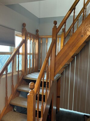 A wooden staircase with a handrail, carpeted steps, and a window with blinds. - Soothing 1-bedroom studio with AC in charming Guttenberg (Guttenberg)
