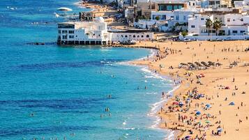 Un pueblo costero con edificios blancos, una playa de arena y aguas azul cristalino.