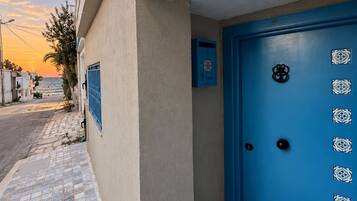 Un edificio con puerta azul, buzón y acera de baldosas.
