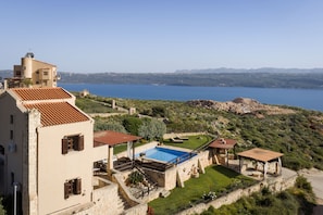 Eine Villa mit Swimmingpool, Steinmauern und Meerblick.