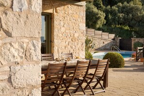 A stone building with a pool, outdoor seating, and a staircase leading to a deck. - VILLA THEA, Your Villa (Chania)