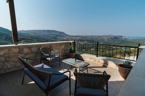 A terrace with wicker furniture and potted plants, overlooking a mountainous landscape. - Villa Elia Provarma, Your Villa (Chania)