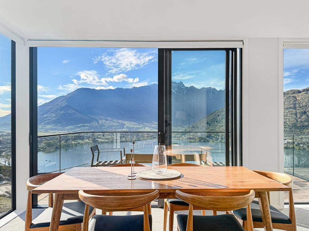 Un comedor con mesa y sillas, ventanas amplias con vista a la montaña.