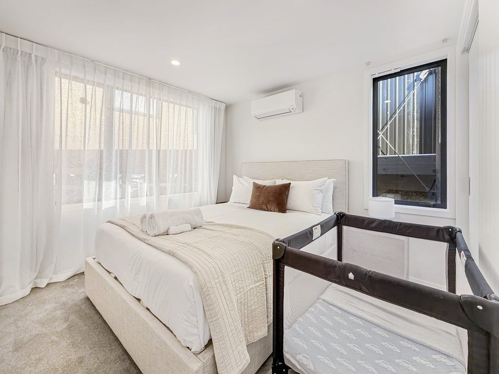 Une chambre à coucher avec un lit, une fenêtre et une vue sur un bâtiment à l’extérieur.