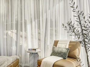 A room with a bed, a side table with books, and a plant.