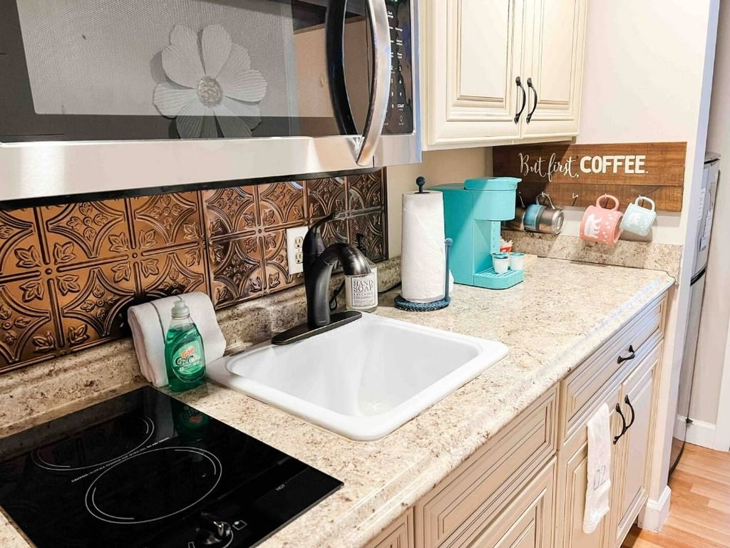 A kitchen with a microwave, stove, sink, and a coffee station.