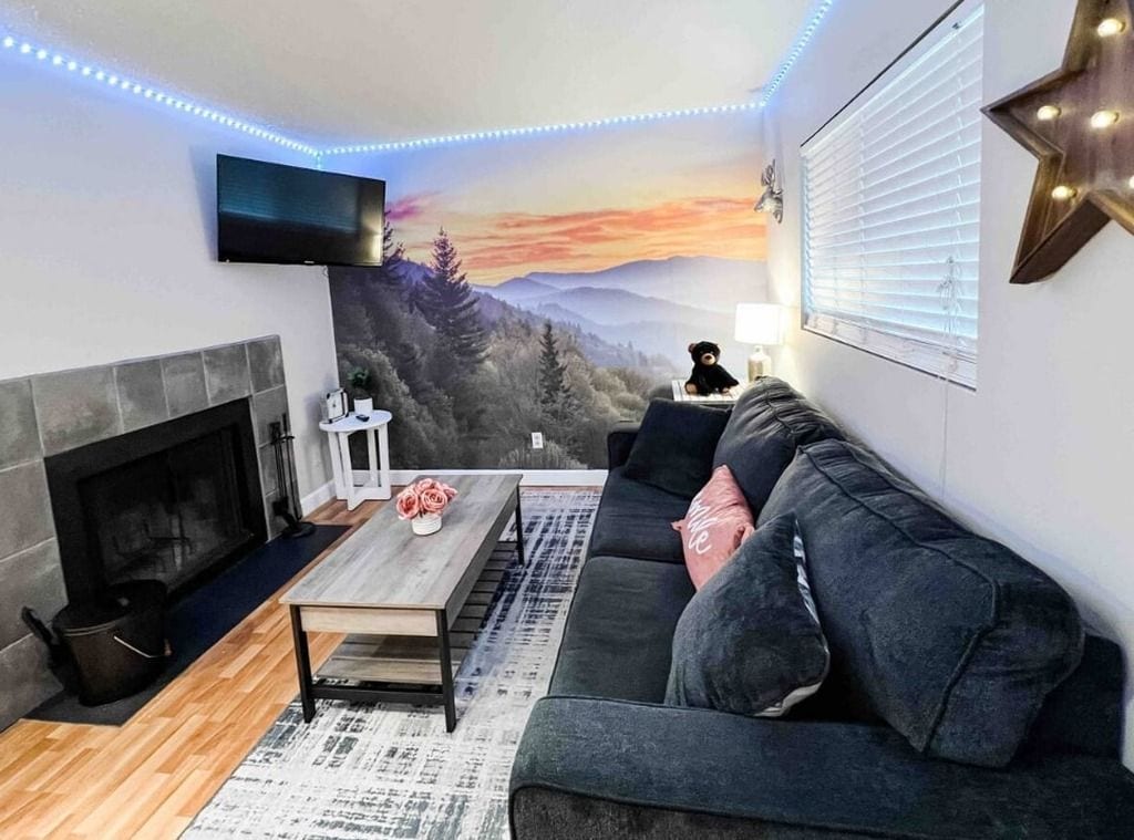 Ein Wohnzimmer mit Kamin, einer Couch, einem Couchtisch und einem an der Wand befestigten Fernseher.