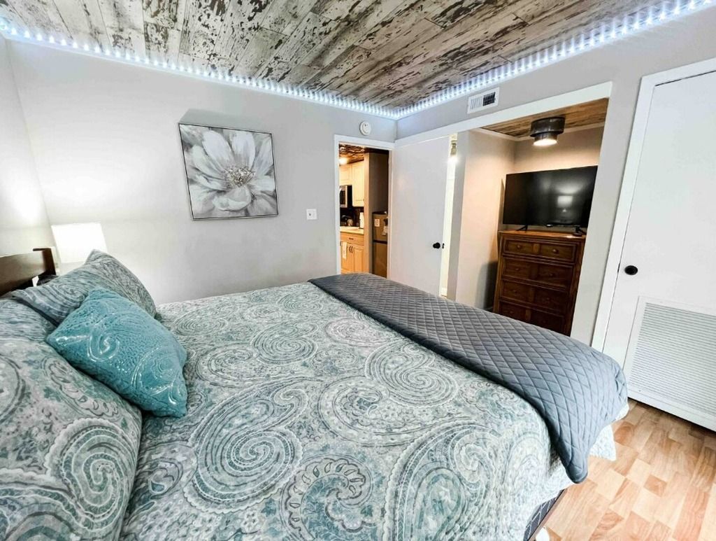Une chambre à coucher avec un lit, un tableau et une vue sur la cuisine.