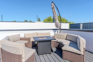 Ein Außenbereich mit Korbmöbeln, einem Tisch, einer Pergola und blauem Himmel.