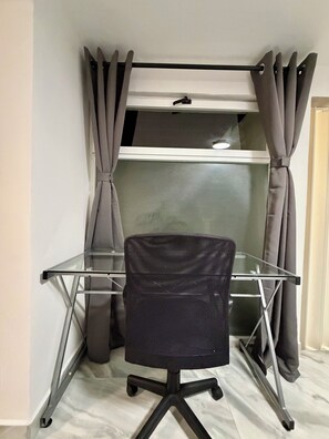 A room with a glass desk, a black office chair, and grey curtains. - New Listing (Naucalpan de Juárez)