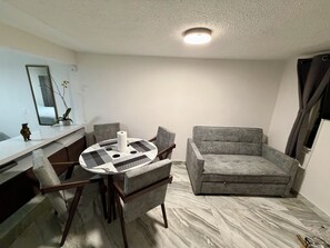 A compact living space with a round dining table, grey sofa, and a ceiling light fixture. - New Listing (Naucalpan de Juárez)